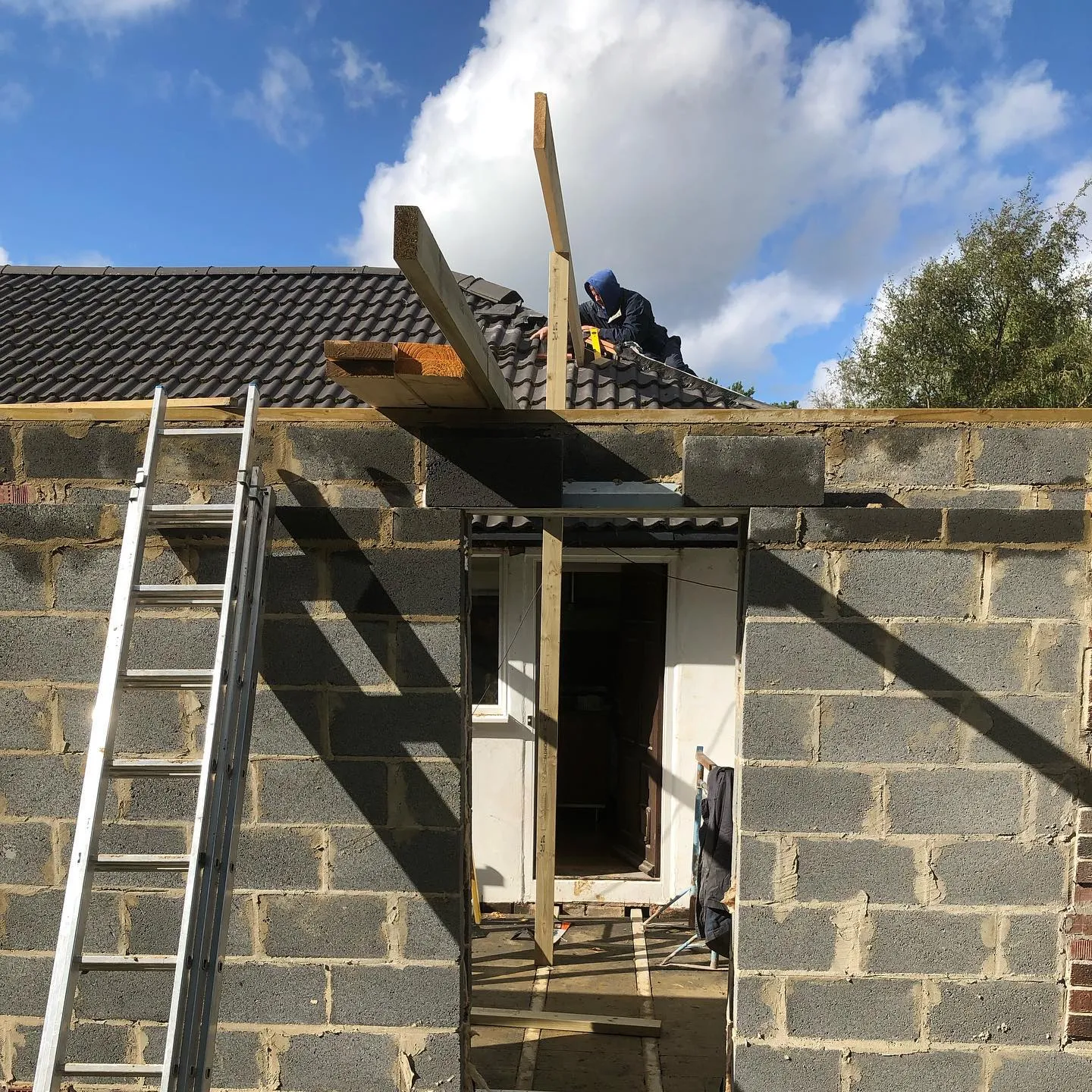 A house being built with a ladder up to it.